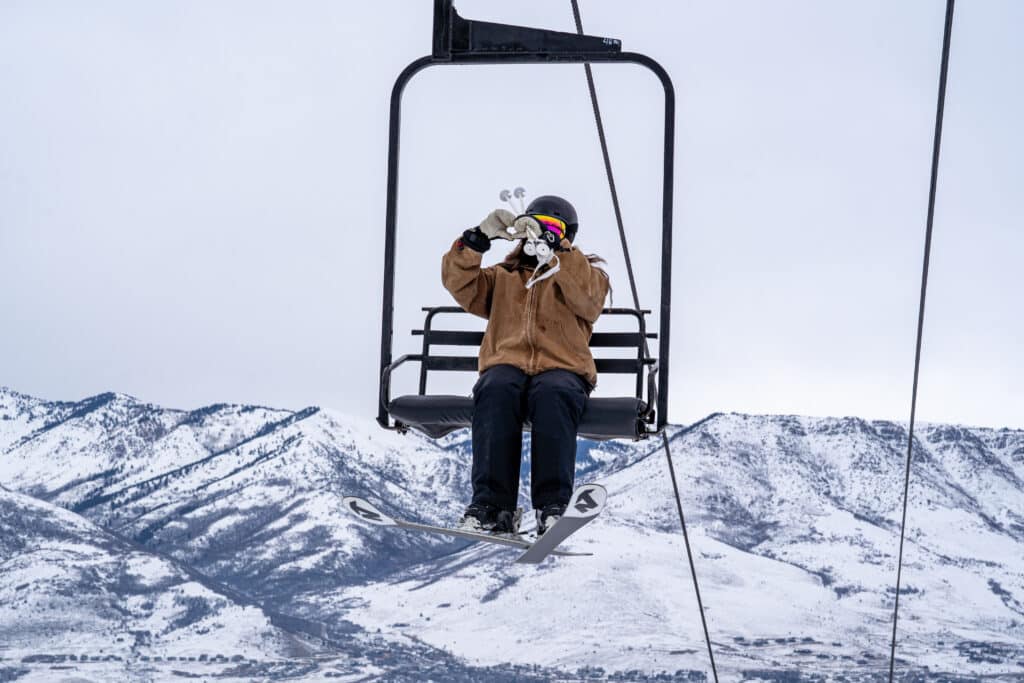 Skier giving a heart shape with her hands on the Apollo Lift at Nordic Valley